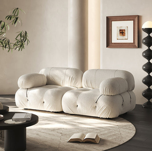 Cream sectional sofa with rounded armrests and plush, tufted cushioning