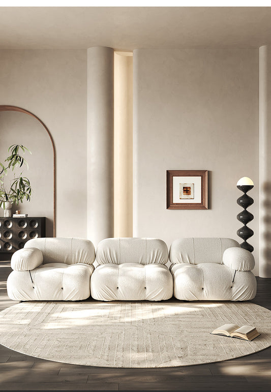 Cream sectional sofa with three rounded seat modules and bolstered back cushions