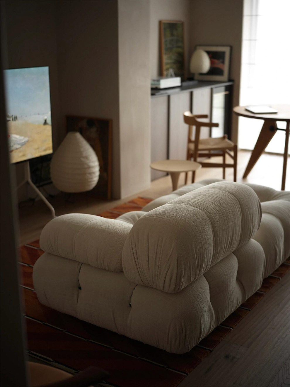 Light beige modular sectional sofa with rounded arms and tufted seat cushions
