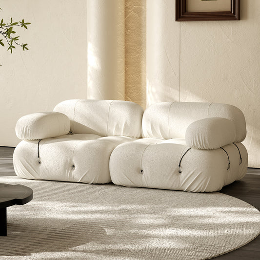Two-seater compressed sofa with curved arms and tufted cushioning, light beige fabric