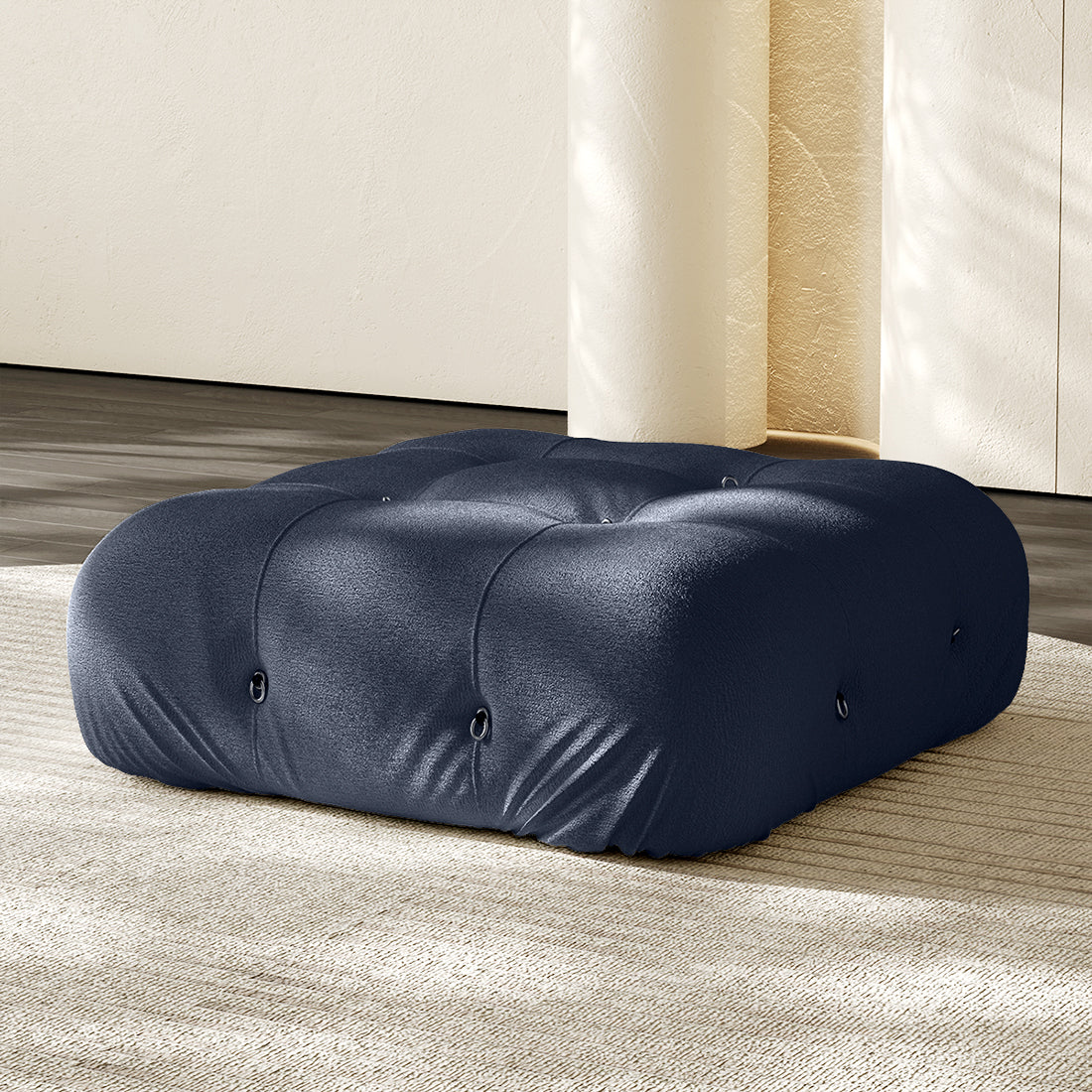 Navy blue square ottoman with tufted button details and plush compression cushioning.