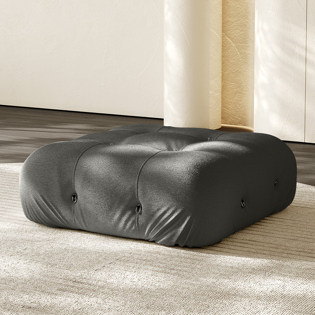 Charcoal gray square ottoman with tufted button details and plush compression cushioning.