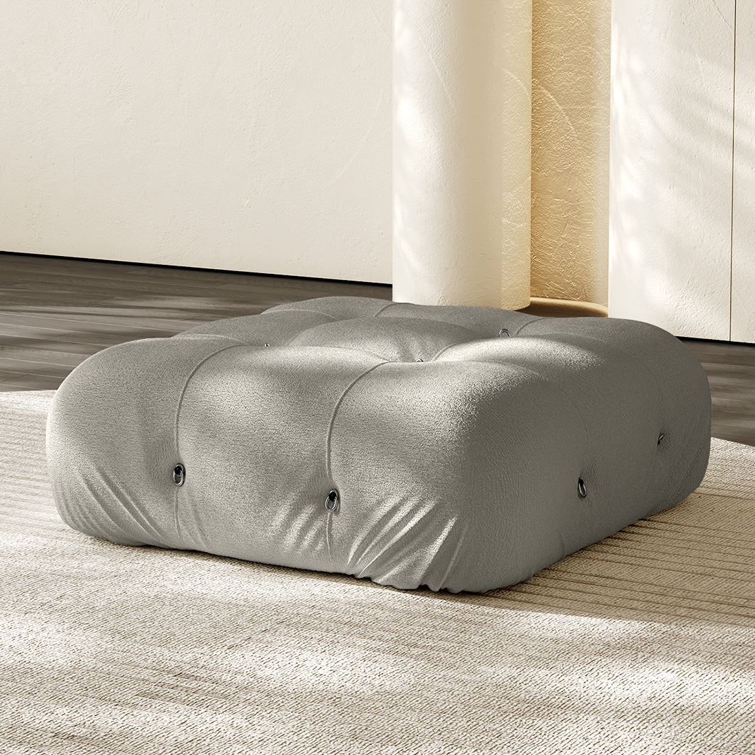 Light gray square ottoman with tufted button details and plush compression cushioning.