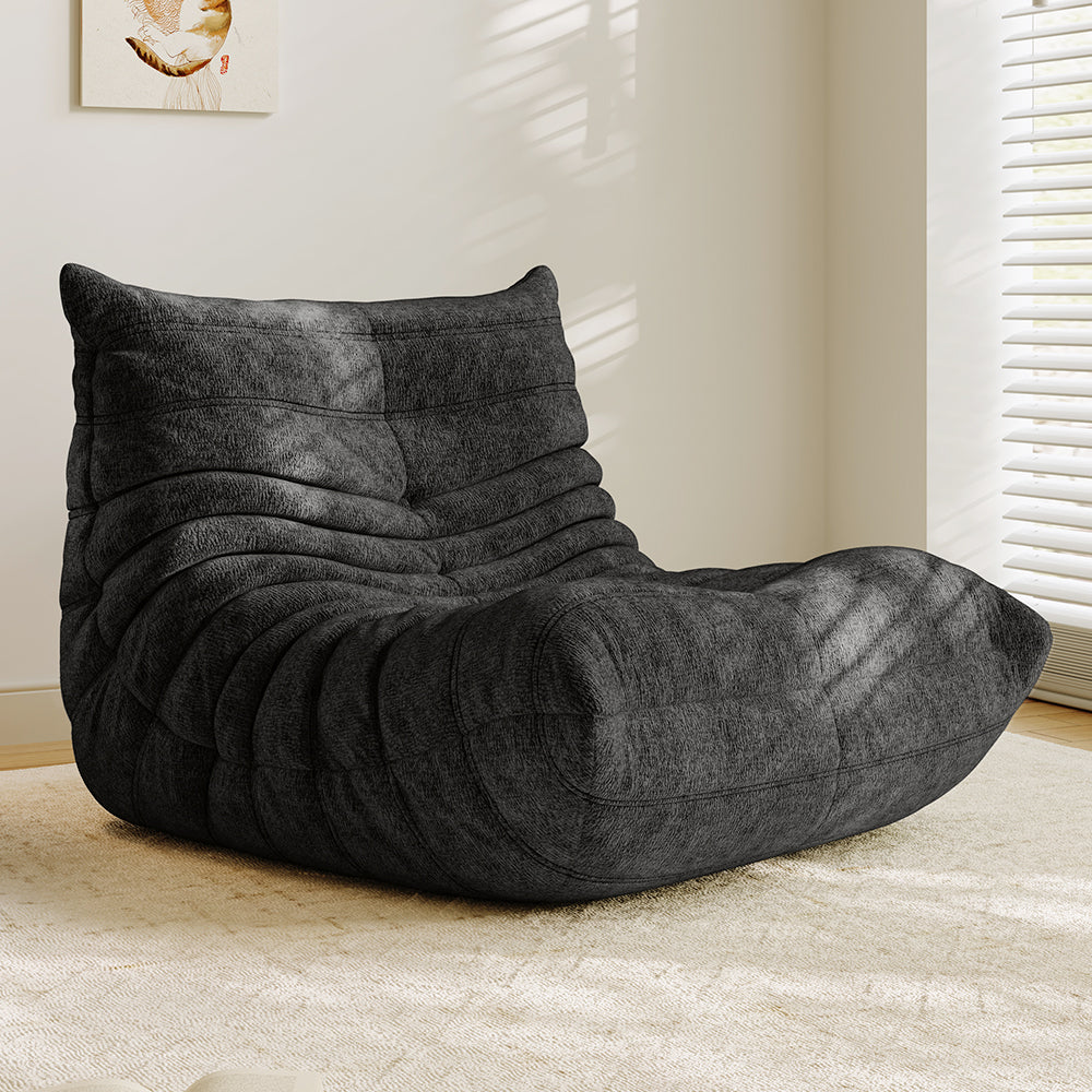 Charcoal gray lounge sofa chair with padded headrest and curved, quilted seat cushion.
