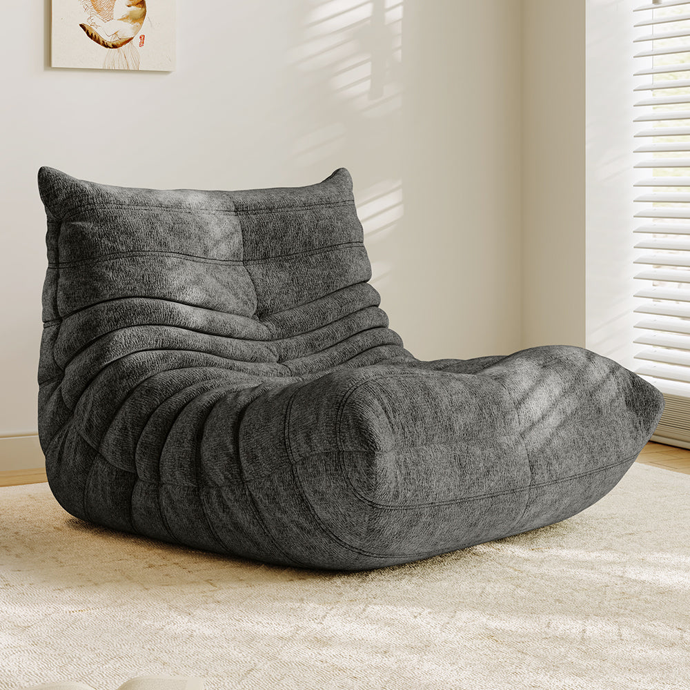 Charcoal gray lounge sofa chair with cushioned armrests and layered curved backrest.