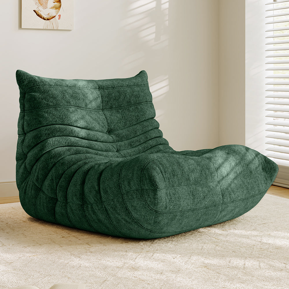 Dark green lounge sofa chair with cushioned backrest and curved seat with quilted layers.