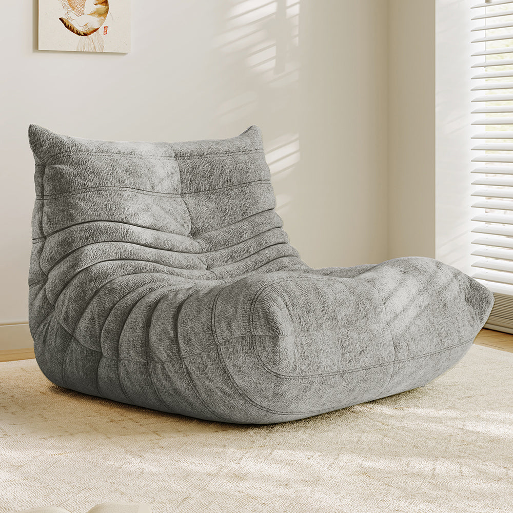Light gray lounge sofa chair with padded headrest, arched seat, and quilted wave panels.