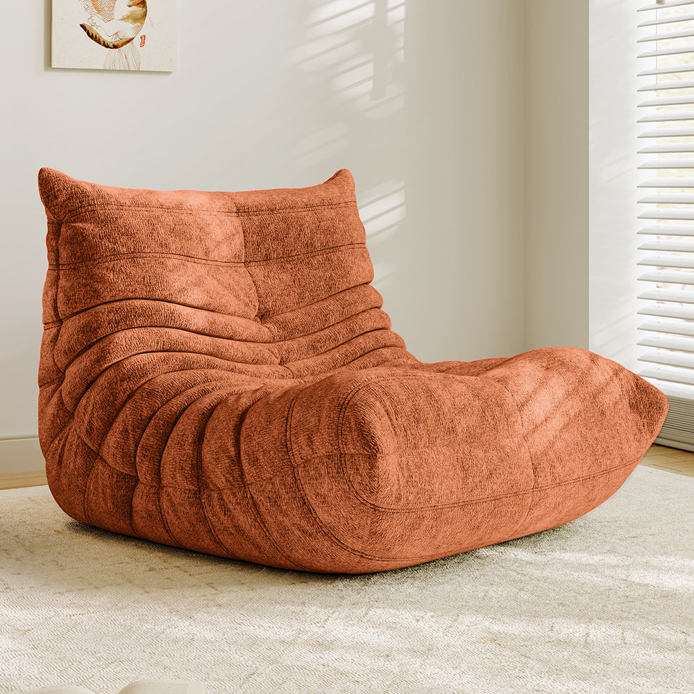 Rust orange lounge sofa chair with padded backrest, arched seat, and curved quilted panels.