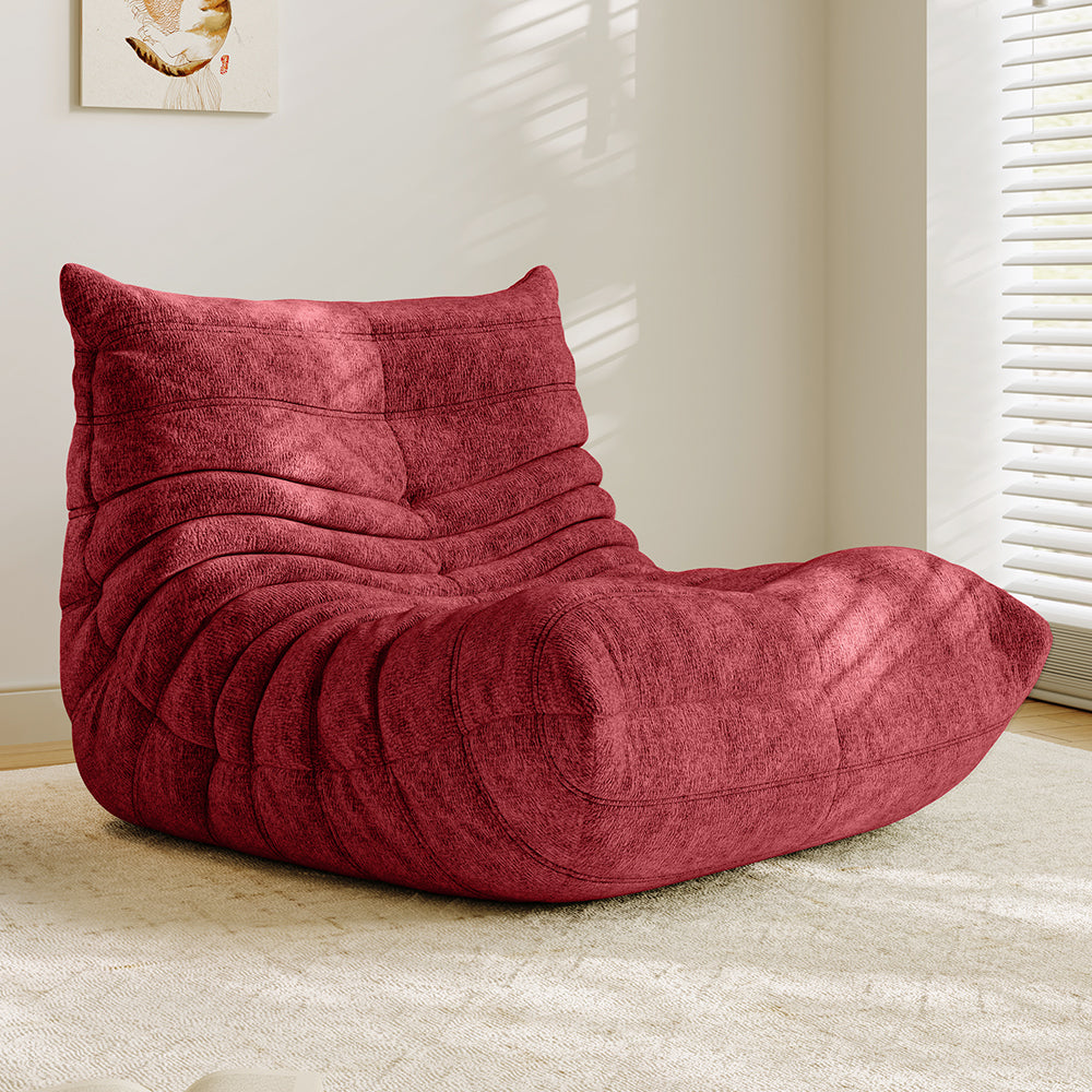 Burgundy red lounge sofa chair with padded backrest and curved seat with quilted stitching.